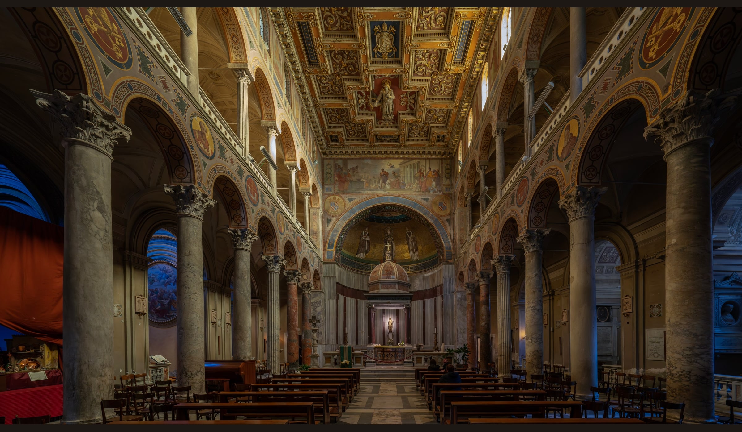 The richly decorated nave, ancient columns, high altar, and apse of the Basilica of Sant’Agnese fuori le Mura in Rome.