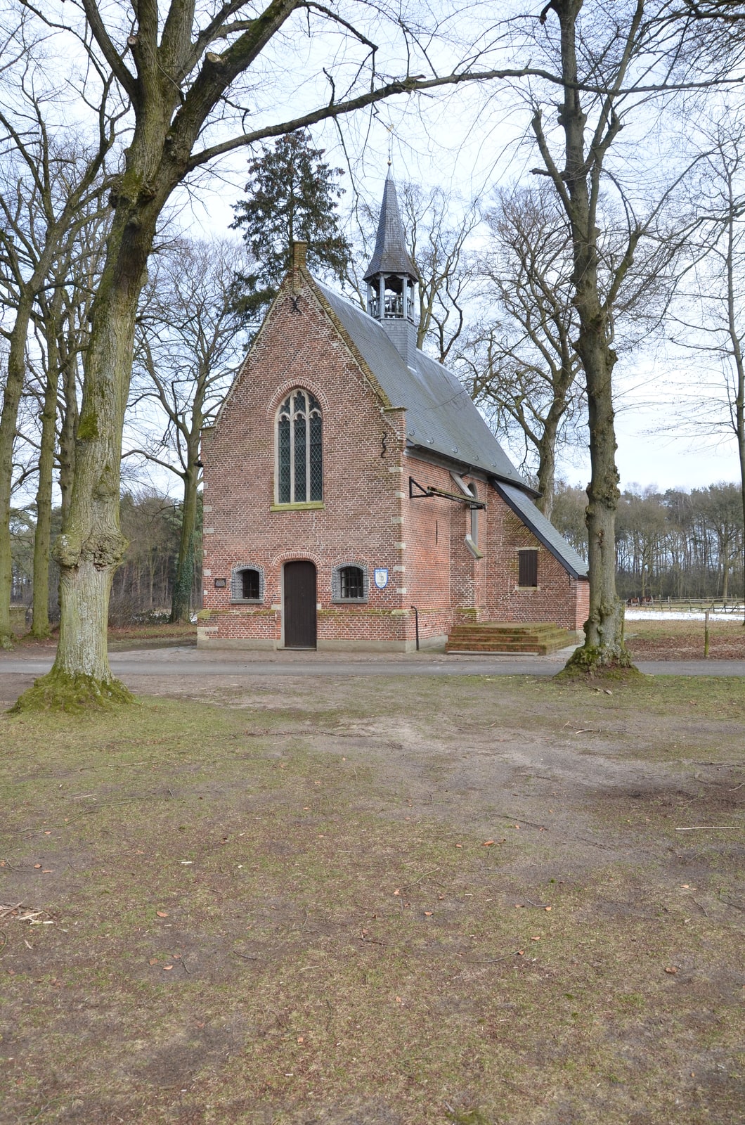 The late-Gothic brick Hegge Chapel standing among mature trees in Poederlee, Belgium.