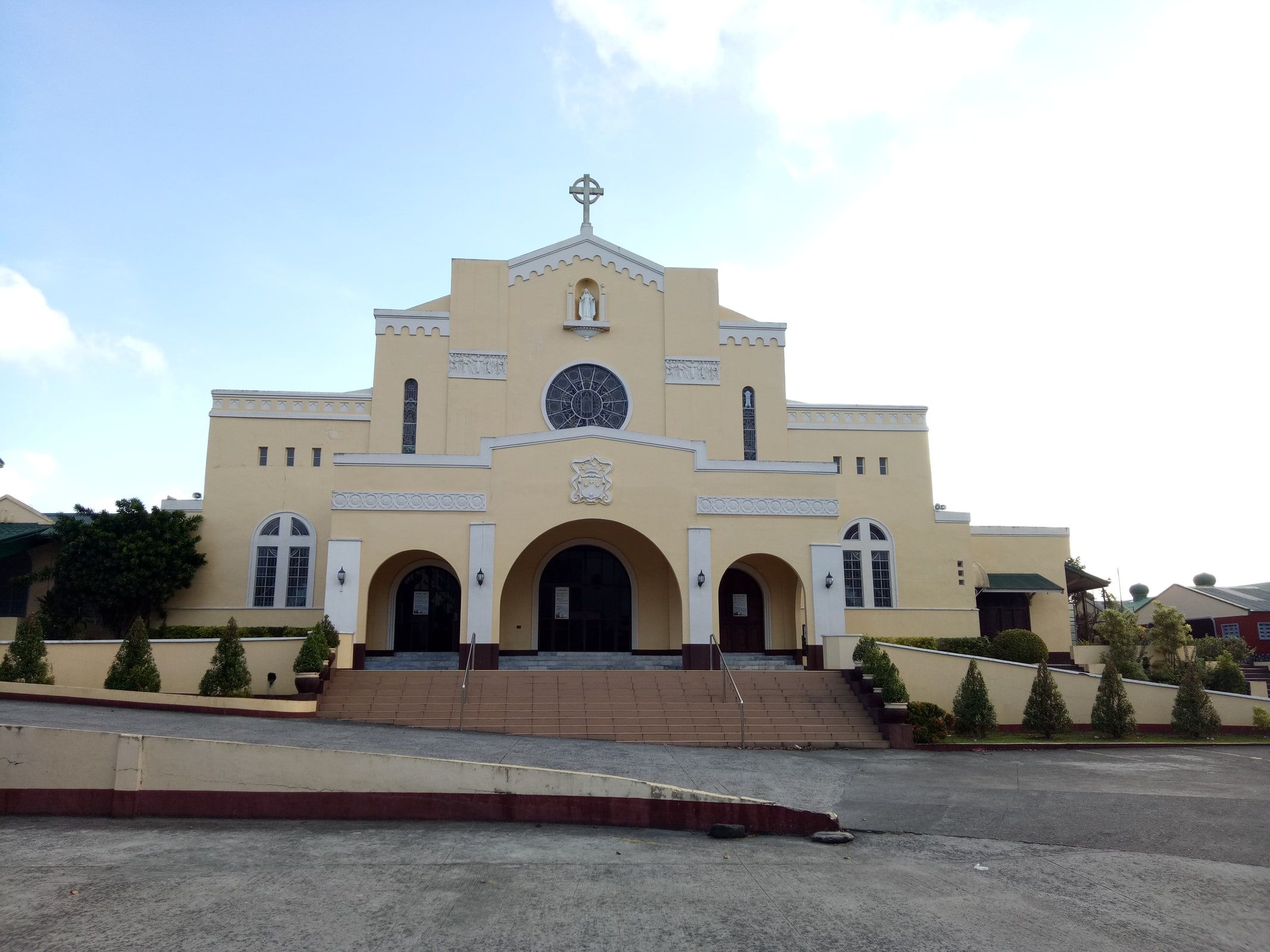 The pale yellow church facade of Lipa Carmel in Batangas, Philippines.