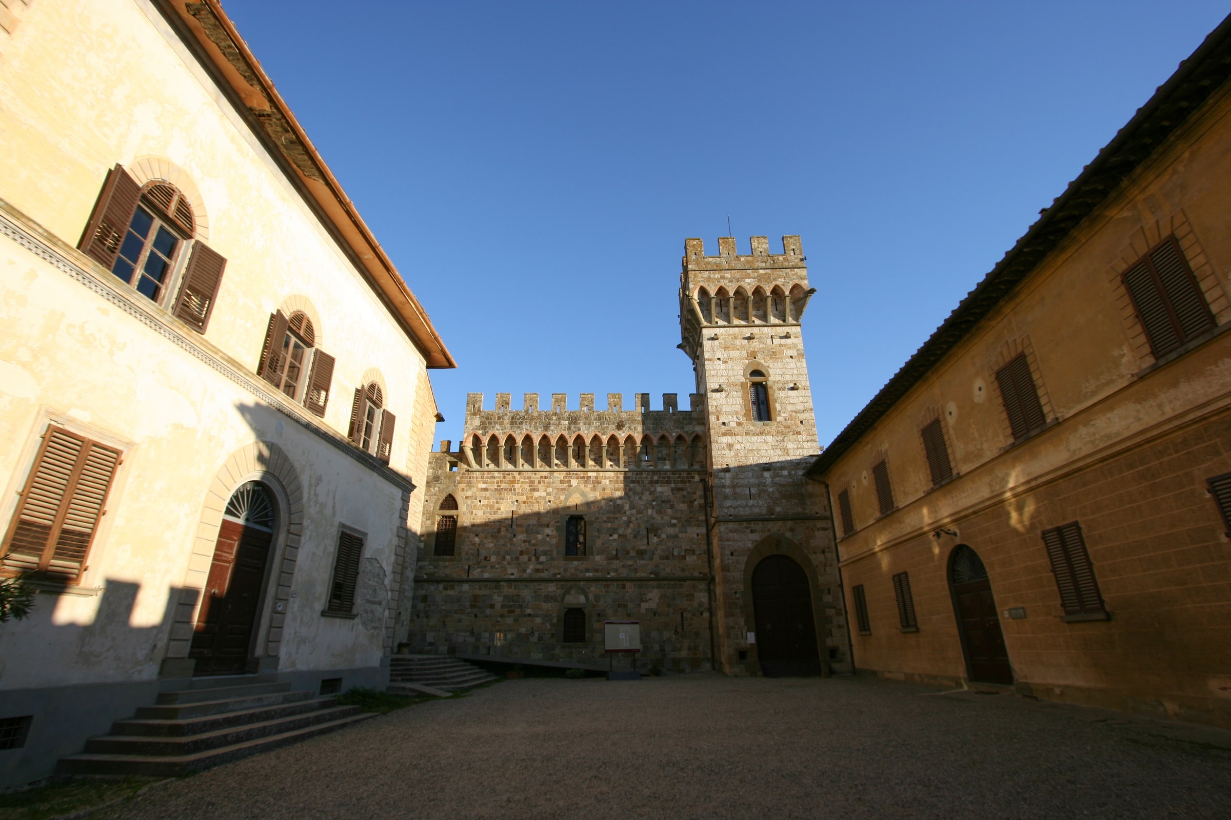 The fortified stone abbey of Badia a Passignano rising above green Chianti vineyards.
