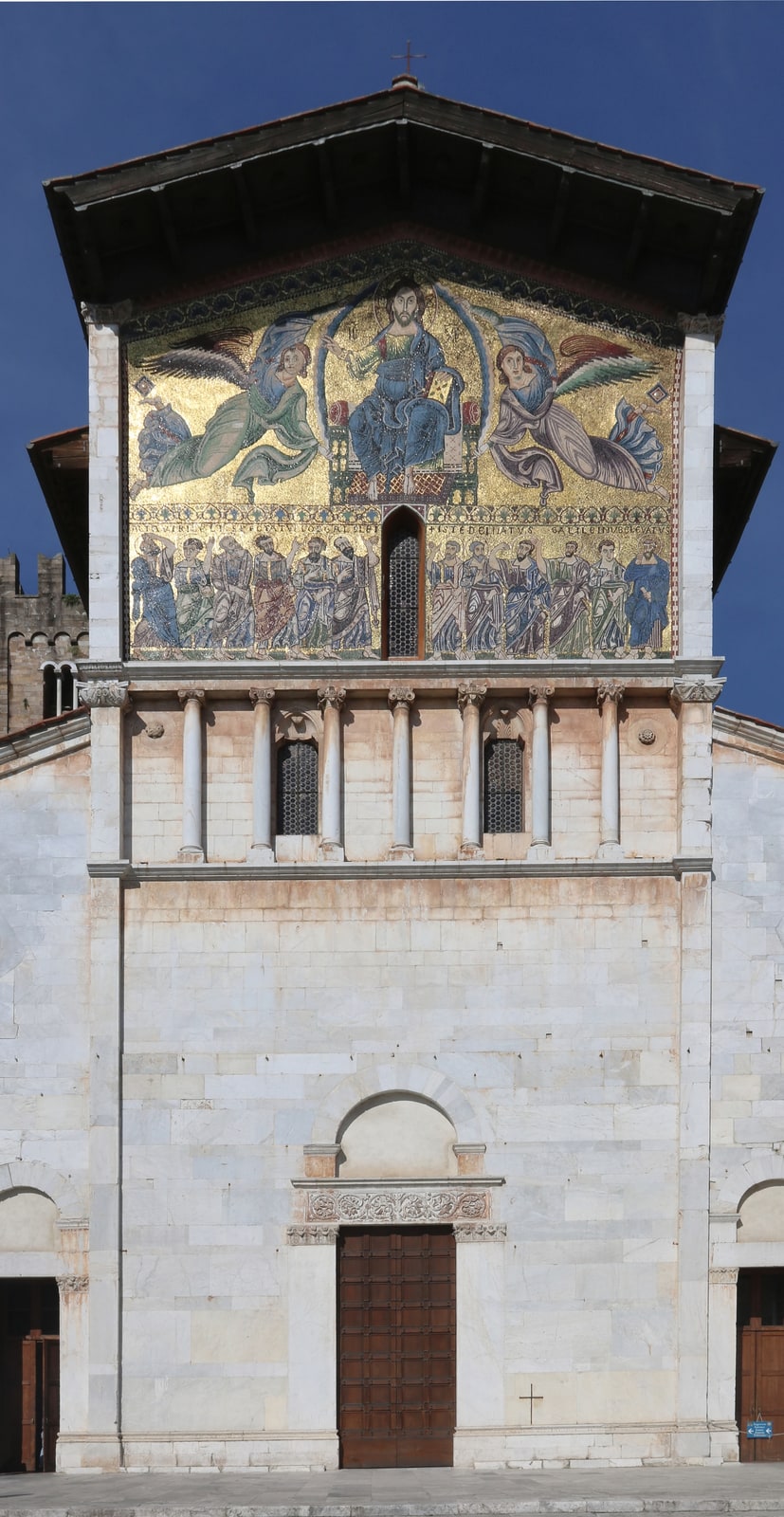 The tall Romanesque facade of San Frediano in Lucca crowned by its golden Ascension mosaic.